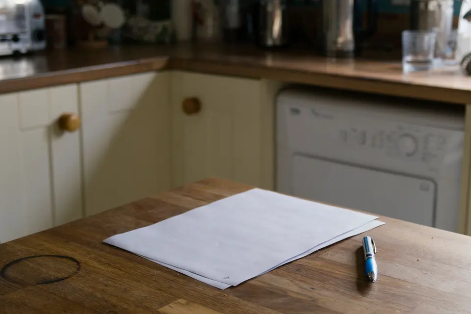 Een vel papier en een pen op een houten keukentafel