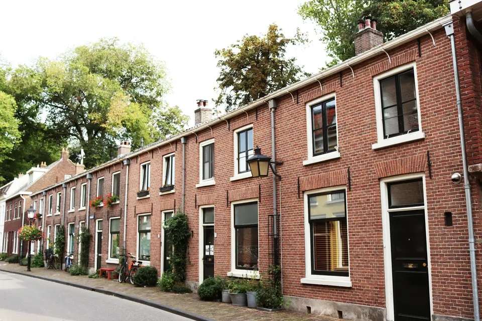 Een rij bakstenen rijtjeshuizen in een rustige Nederlandse straat