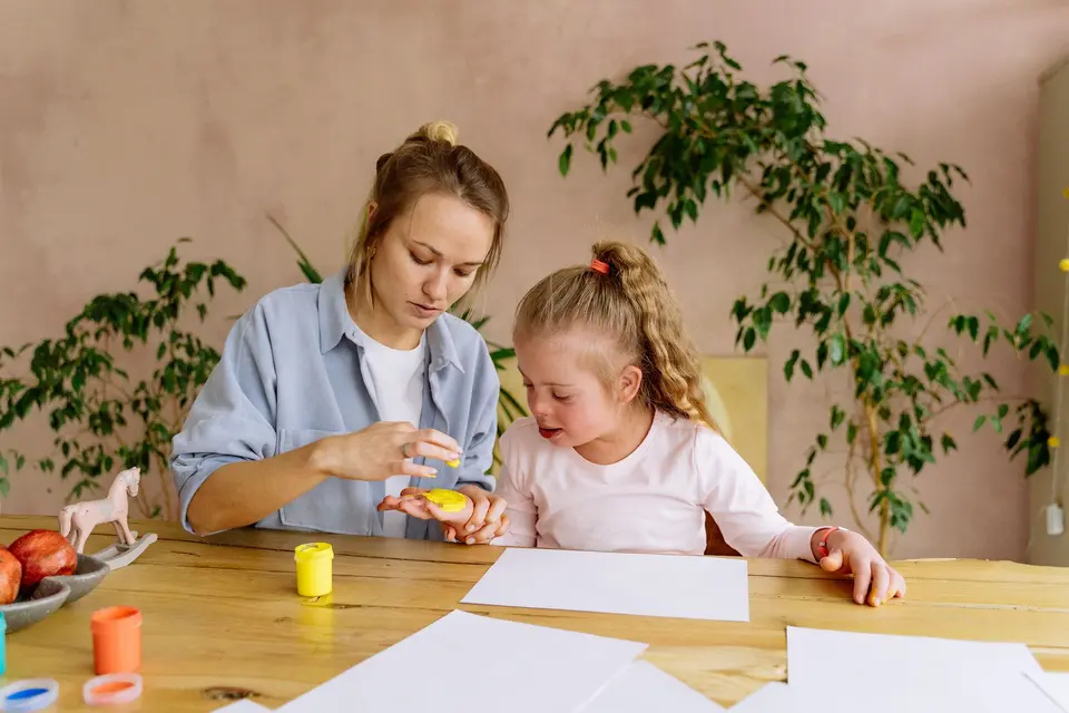 Een moeder en haar dochter met downsyndroom zijn samen aan het knutselen aan de keukentafel